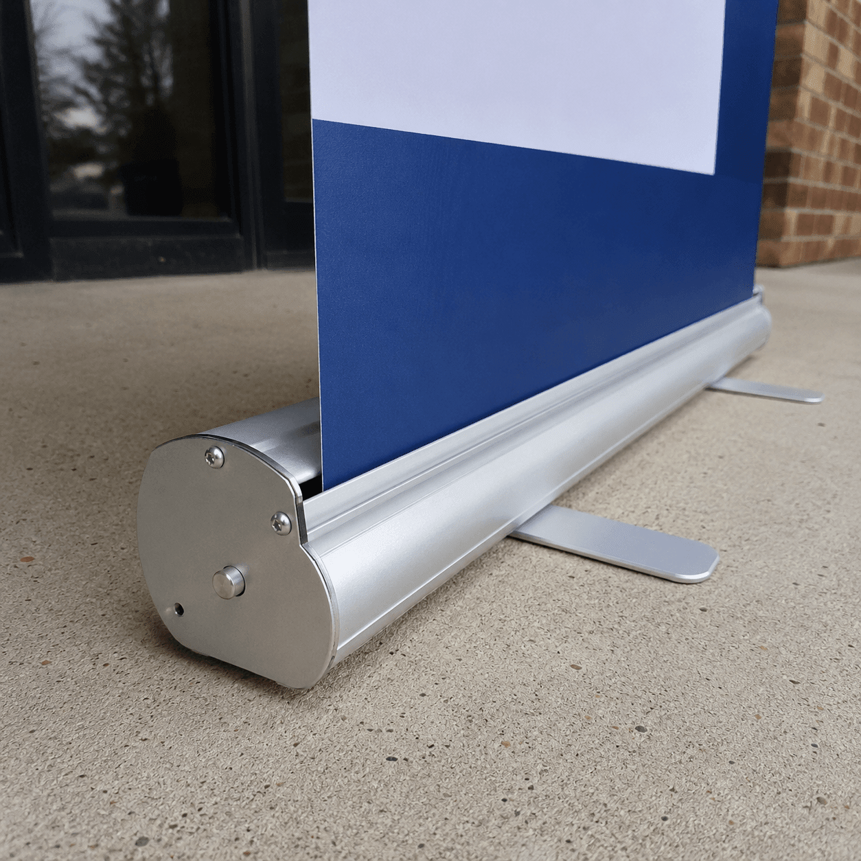Blue and white sign on a retractable  banner stand outdoors with a building in the background